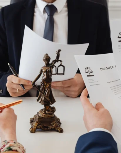 Spotkanie z prawnikiem przy biurku z dokumentami i statuetką Temidy, podczas którego omawiane jest to, jak odzyskać koszty kredytu od banku poprzez sankcję kredytu darmowego.