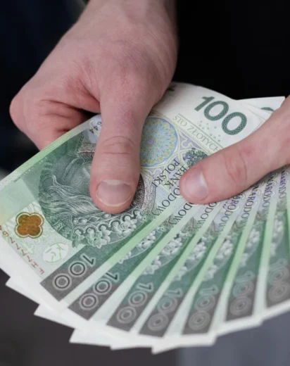 Mężczyzna trzymający w dłoniach banknoty 100 złotych po ogłoszeniu planu spłaty po upadłości.